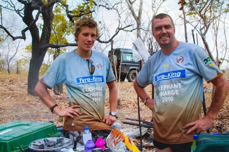 Two team members in Elephant Charge 2010 shirts at a camp table in the bush