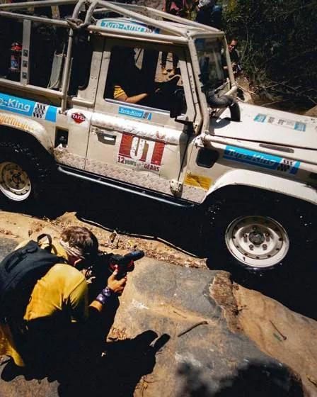 Photographer crouching next to an off-road rally car